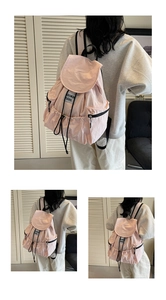 Close-up of pink nylon backpack featuring drawstring closure and side zipper pockets