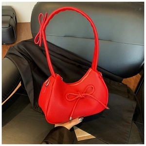Detail of red lychee textured hobo bag with stylish bow accents on black leather seat