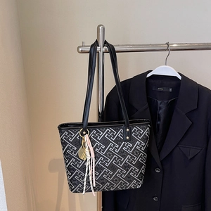 Detail of grey tote bag with geometric embroidery, gold tennis racket charm and tassels
