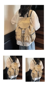 Detail of beige nylon drawstring backpack with flap closure and side zipper pockets