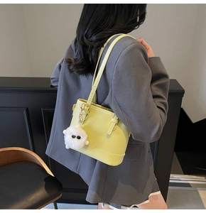 Detail of lime green bucket bag with plush charm and brand text on shoulder