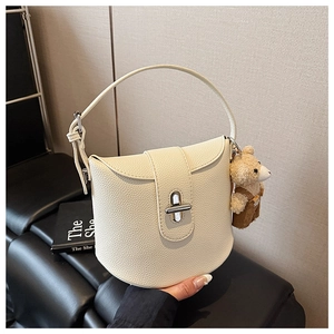 Close-up of off-white lychee grain handbag with a silver lock and cute bear charm