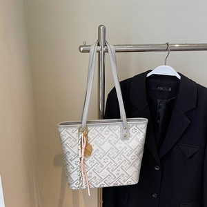 Detail of grey jacquard tote bag with floral patterns and a decorative tassel charm