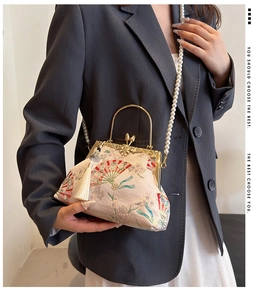 Detail of vintage embroidered shell bag with metal handle, tassel, and pearl strap