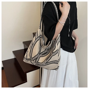 Detail shot of the printed canvas tote bag with chain pattern on a female model
