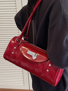 Sac à épaule en cuir verni rouge avec pendentif cœur dans une scène de style de vie