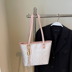 Detail view of pink leather trim and textured fabric tote with stylish coin tassel charm