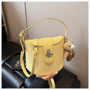 Detail of yellow lychee leather bucket bag with silver rotating clasp and bear charm