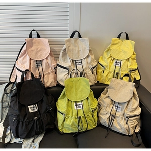 Selection of colorful nylon backpacks in pink, yellow and green on a dark leather bench