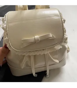 Détail d'un sac à dos blanc cassé avec dentelle et nœud papillon sur similicuir brillant
