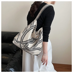 Detail view of a large vintage canvas tote bag with black chain print on a model