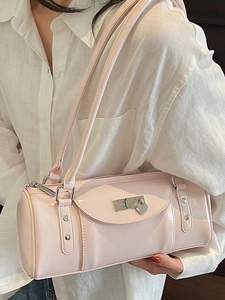 Sac baguette cylindrique en cuir verni rose avec charm cœur sur chemise blanche
