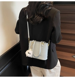 Detail of light blue bucket bag with plush charm on a wooden staircase background