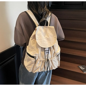 Detail of cream nylon drawstring backpack with flap closure and minimalist brand label