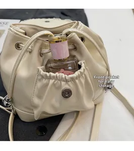 Détail du sac seau beige à cordon avec une poche avant pour ranger le parfum
