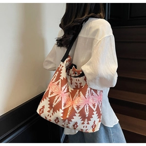 Detailed view of canvas tote bag with orange geometric patterns shown on shoulder