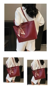 Detail der roten Ledertasche mit elegantem Blumentuch am Griff und goldenem Logo
