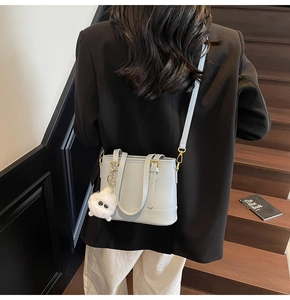 Detail of light blue bucket bag with gold hardware and plush ball on wooden stairs