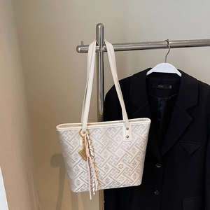 Detail of off-white tote bag with geometric floral jacquard and a tassel abacus pendant
