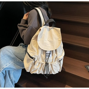 Detail view of cream nylon drawstring backpack with side zipper on model on stairs