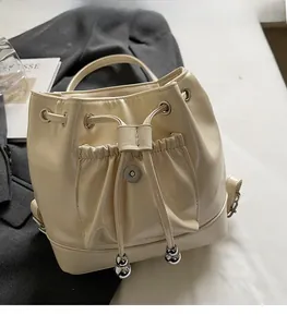 Détail du sac à dos seau blanc crème avec cordon de serrage et pendentif en métal argenté