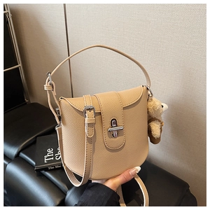 Close-up of beige lychee grain faux leather handbag with silver metallic twist-lock and bear charm