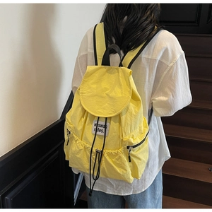 Detail of a bright yellow nylon backpack with drawstring closure and white fabric label
