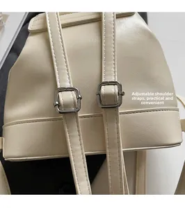 Détail des bretelles réglables avec boucles argentées sur le sac à dos blanc crème