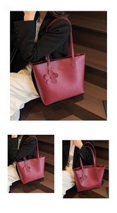Detaillierte Makroansicht der burgunderroten Shopper-Tasche mit Blumenanhänger und Goldlogo