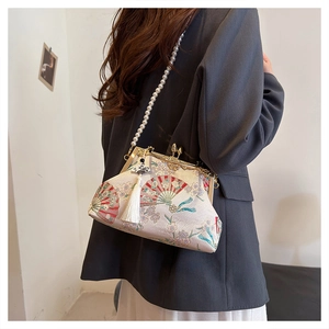 Detail of elegant Chinese embroidery with red fan and pearl strap on ivory evening bag