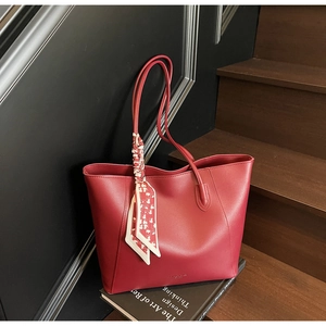 Detail der roten Leder-Tote-Bag mit glatter Textur und floralem Seidentuch am Griff