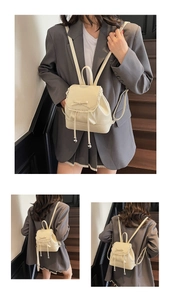Détail d'un mini sac à dos blanc crème avec bordure en dentelle, nœuds et perles
