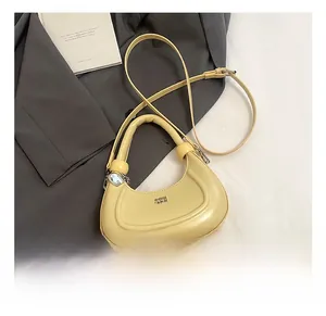 Detailed close-up of yellow crescent leather handbag on a grey blazer suit jacket