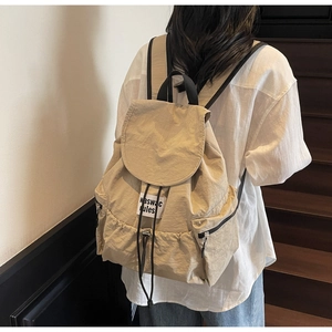 Detail view of khaki nylon drawstring backpack with signature text patch and flap design