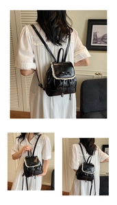 Détail du mini sac à dos en cuir noir avec bordure en dentelle blanche et noeud
