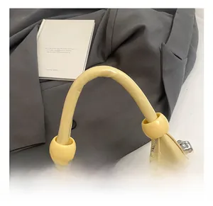 Detail of a beige crescent handbag with thick comfortable handle and silver chain accent