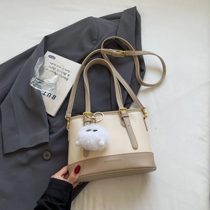 Close-up of contrast bucket bag with pom-pom charm and golden metal buckle details