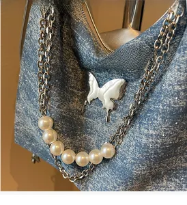 Close-up of sparkling denim tote bag with silver butterfly and pearl chain strap