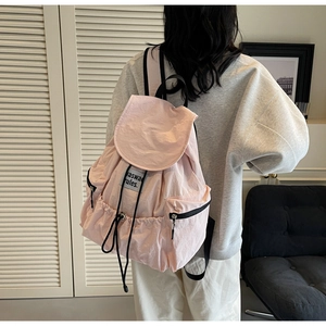 Detailed view of light pink nylon backpack with drawstring closure and black straps
