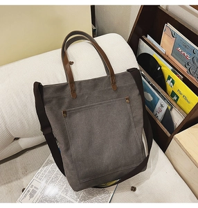 Detail of dark grey canvas tote with brown leather handles and metal rivet pocket decoration