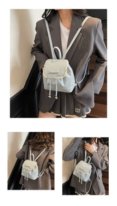 Détail d'un mini sac à dos bleu clair avec bordure en dentelle blanche et nœud