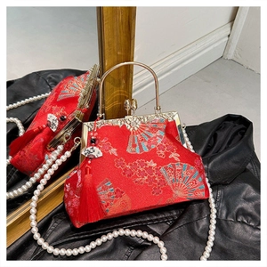 Close-up of red Chinese silk handbag with golden handle and floral embroidery details