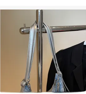 Detail of blue denim shoulder bag with silver leather straps and decorative chains