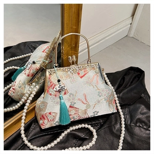 Detail of blue embroidery handbag with golden handle, pearl chain and teal silk tassel
