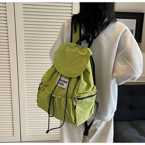 Detail of the avocado green nylon backpack featuring a drawstring closure and a white label