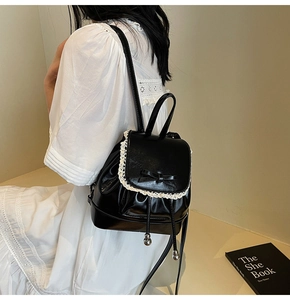 Détail du mini sac à dos en cuir noir avec bordure en dentelle et nœud papillon