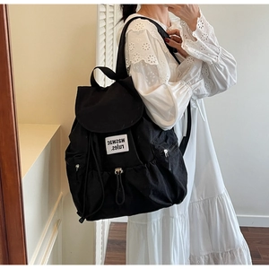 Detailed view of durable black canvas backpack featuring drawstring closure and logo patch