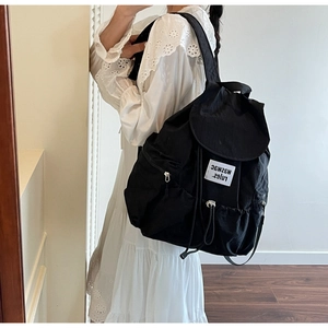 Detail of nylon backpack featuring drawstring closure and stylish white letter patch