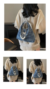 Detail of blue denim backpack with silver chains, pearls and butterfly pendant charm