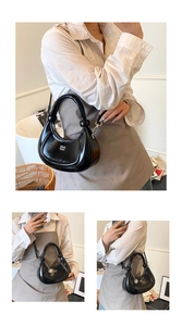 Detailed macro view of the black crescent bag with glossy patent leather and silver metal hooks